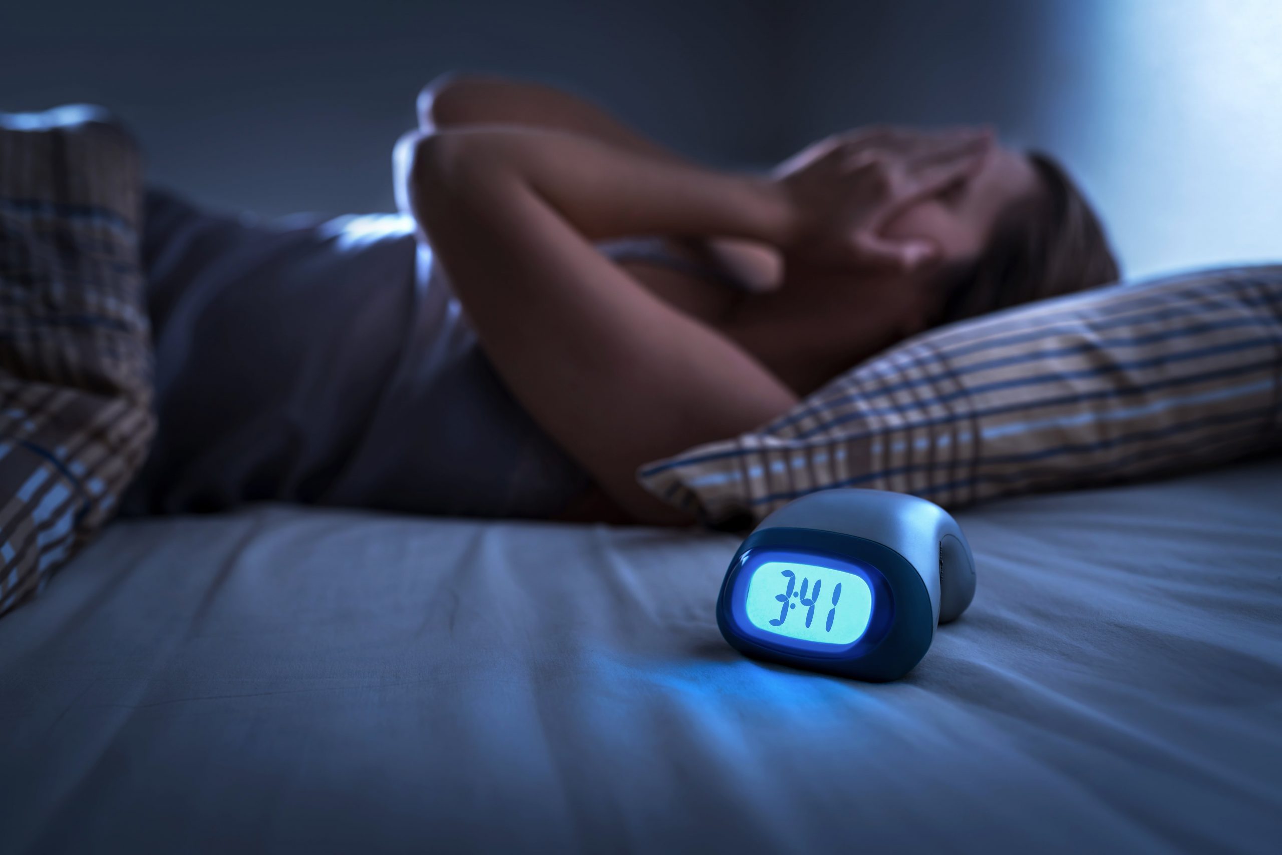 girl with insomnia lying in bed in front of an alarm clock