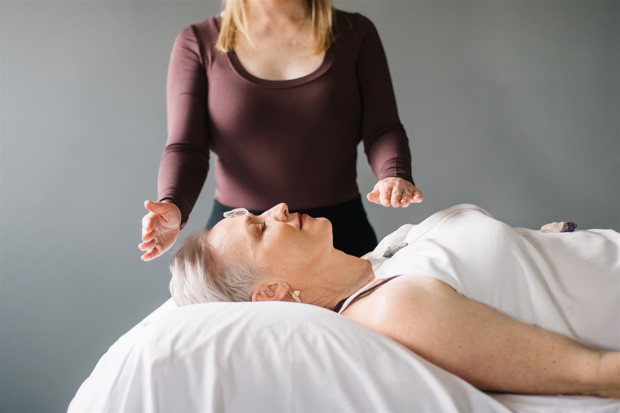 person performing reiki on a person laying on a bed