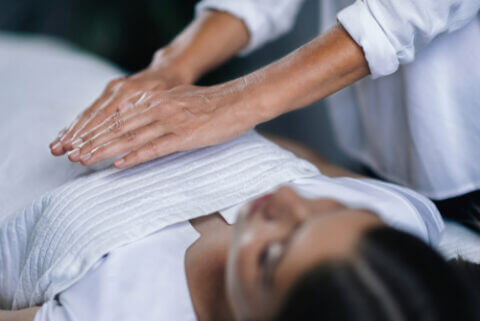 Therapist using reiki healing on abdomen of a female patient