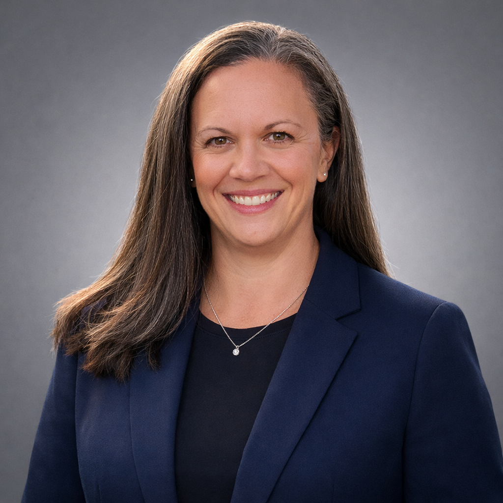 Headshot of Dr. Michelle Winton, Acupuncturist and RMT, smiling in a navy blazer against a neutral gray studio background.