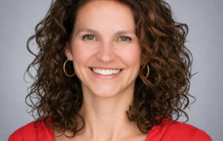 Professional headshot of Dr. Lorraine McCarthy, naturopathic doctor, smiling against a soft grey studio background.