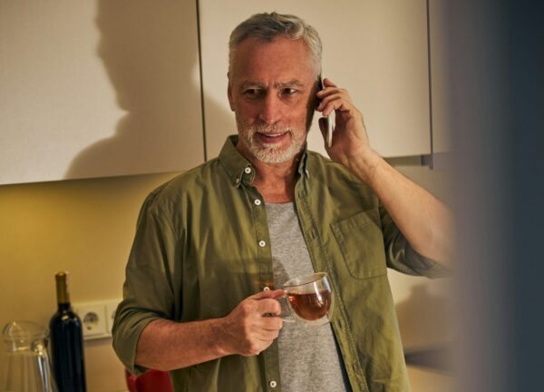 photo - a man with grey hair talking on the phone and ordering a testosterone test canada in the kitchen