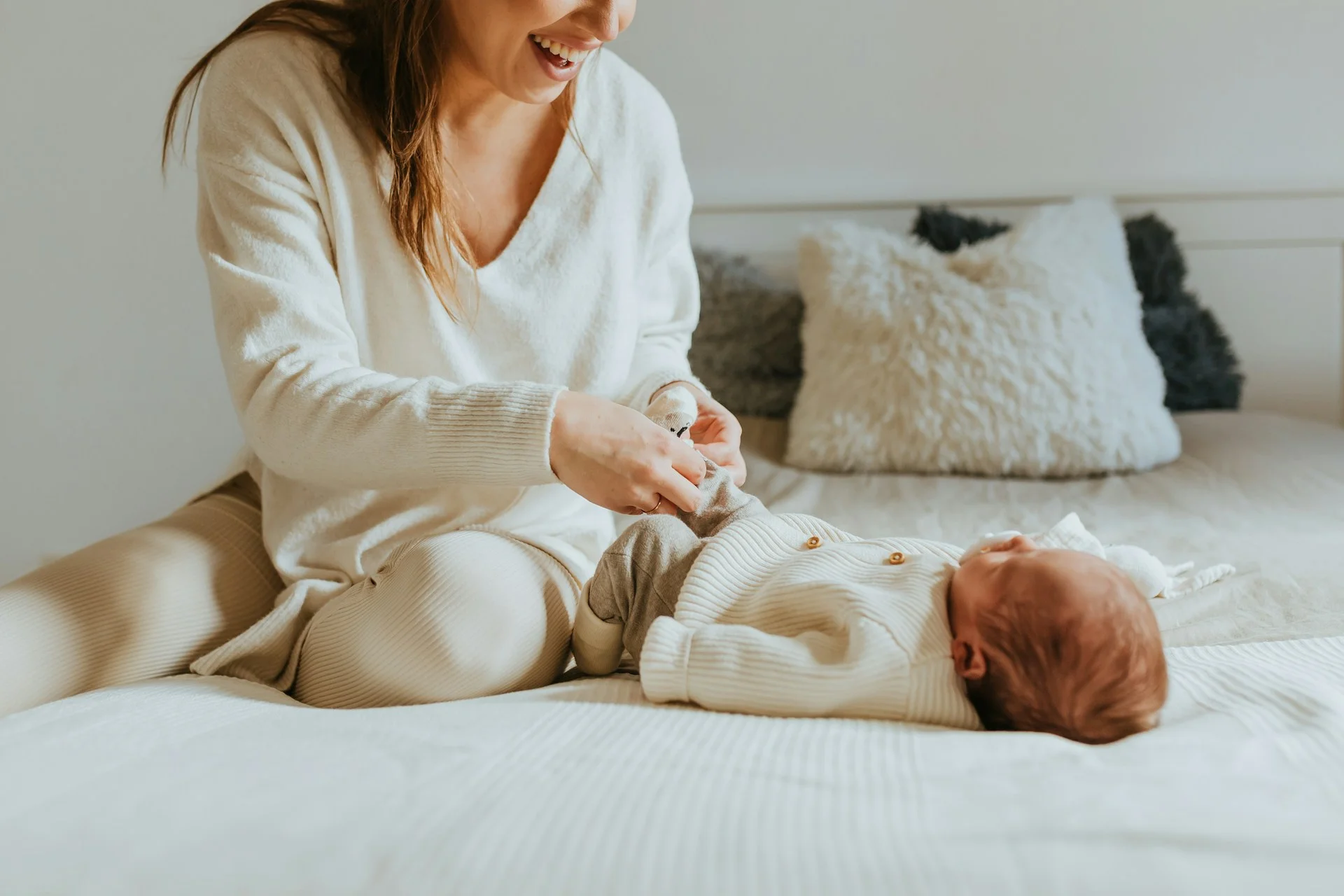 photo - a new mother playing with her newborn baby before her postpartum massage appointment