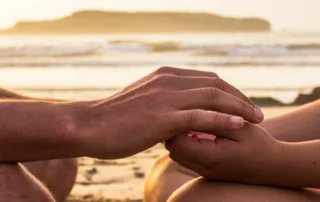 photo - two people holding hands by the ocean shore and considering fertility and naturopathic medicine