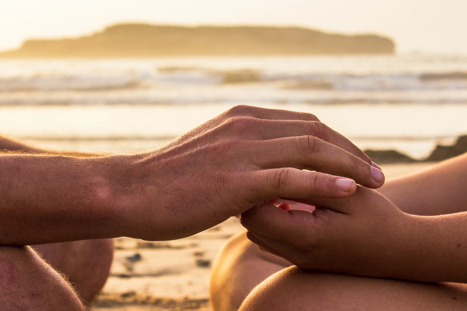 photo - two people holding hands by the ocean shore and considering fertility and naturopathic medicine