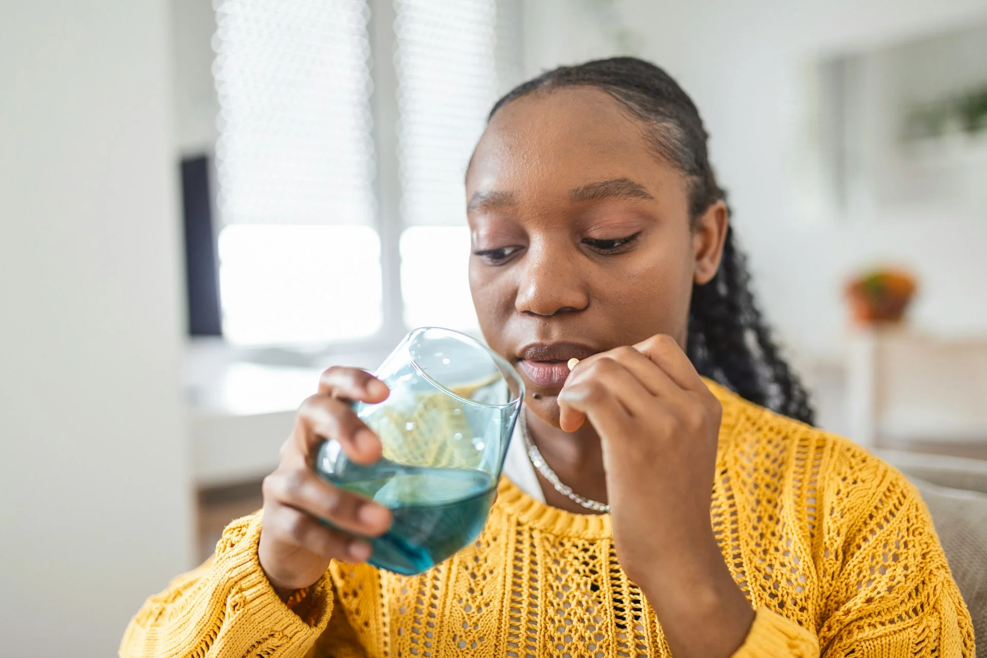 photo - a woman looking at her glass of water while taking homeopathic remedies for gerd acid reflux