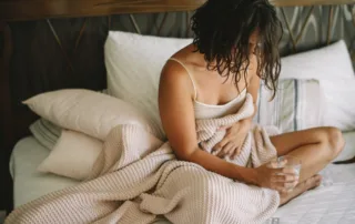 photo - a woman sitting in bed and wondering how to prevent uti when you feel it coming