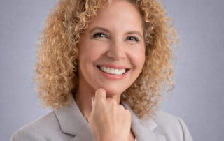 Smiling Nurse Practitioner Stacy Recalla in a white medical coat at Red Leaf Wellness Edmonton