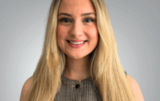 A professional headshot of Kathleen Stagg, Office Administrator and Patient Care Coordinator at Red Leaf Wellness, smiling with long blonde hair and wearing a plaid sleeveless top against a light gray background.
