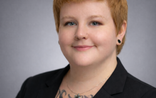 Professional headshot of Kristie Harrison, RMT and MOT, wearing a black blazer against a neutral gray studio background.
