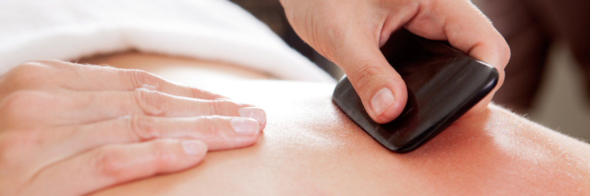 Gua sha smooth-edged tool being applied to reduce inflammation and promote lymphatic drainage at Red Leaf Wellness Edmonton