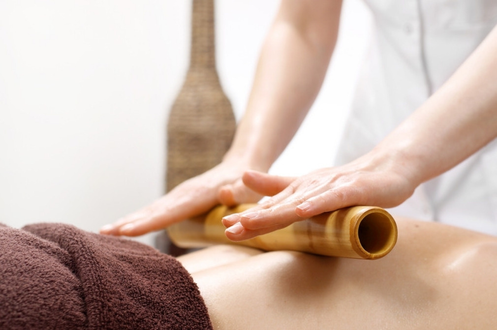 Massage therapist rolling a warm bamboo tool along a draped client's back at Red Leaf Wellness Edmonton